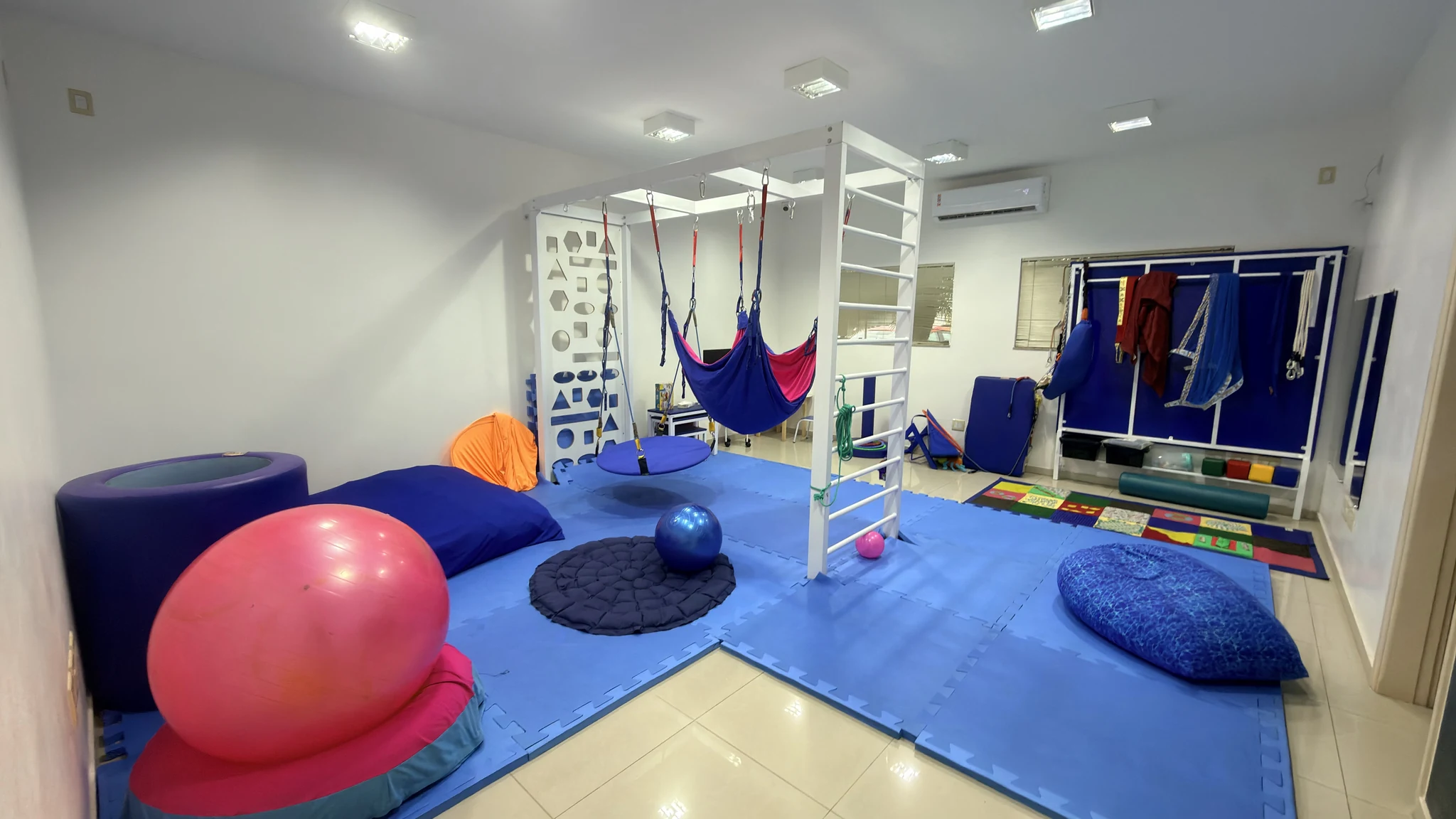 Sala de integração sensorial com rede de casulo, balanço suspenso e tatame